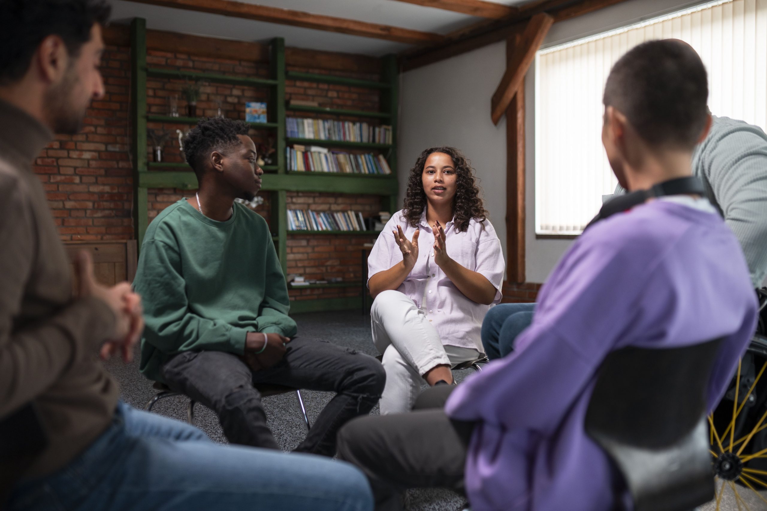 Um grupo de pessoas diversas realiza terapia em grupo representando uma discussçao sobre transtornos mentais e trabalho